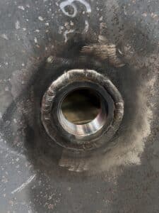 Soudure circulaire précise d'une douille filetée sur une plaque d'acier industrielle.